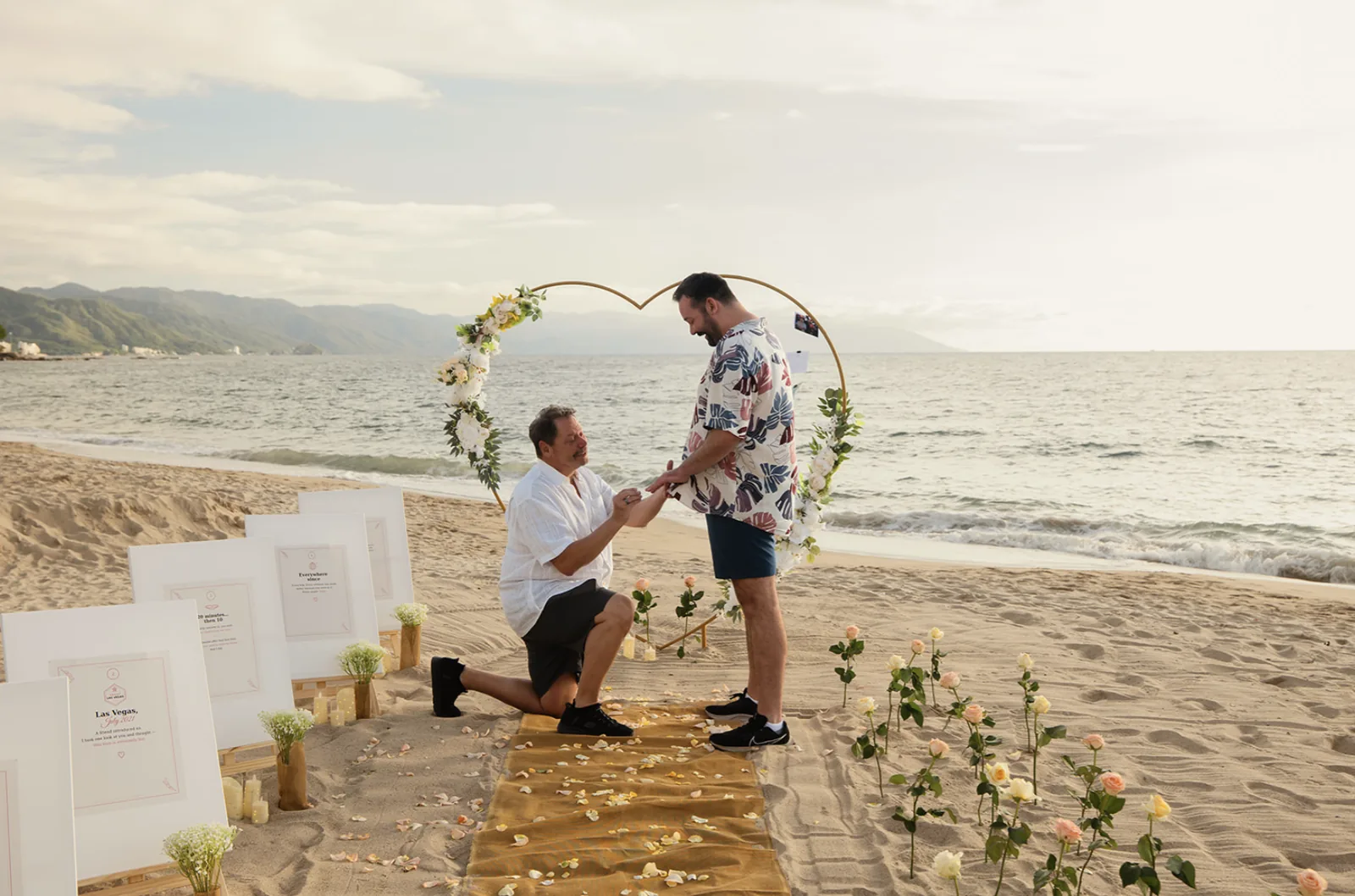 Couple during their proposal under a floral arch on a Puerto Vallarta beach